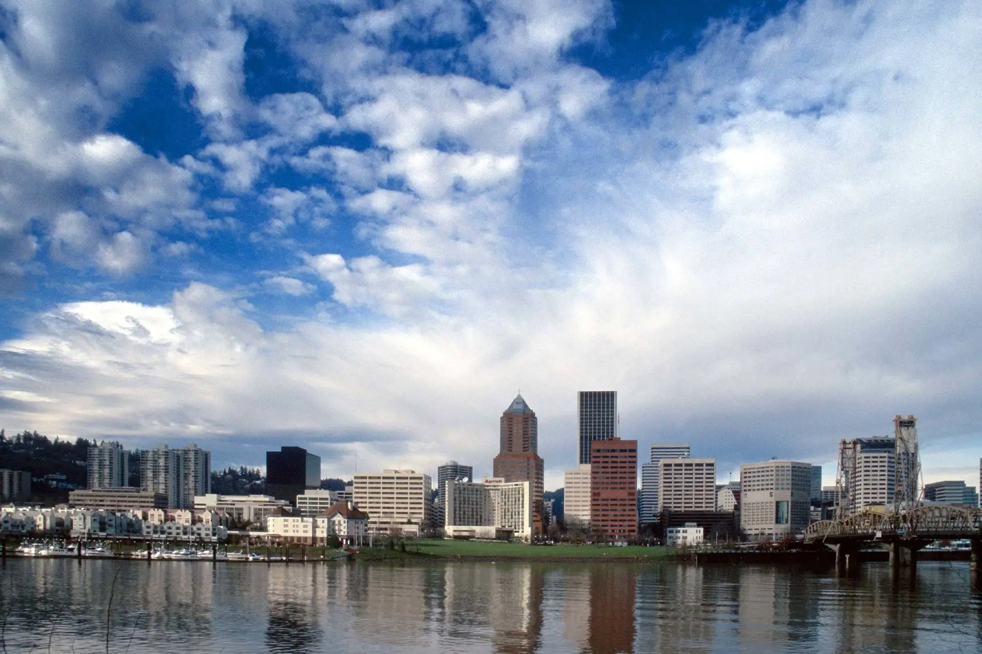 vibrant city skyline reflected in water, highlighted by a dynamic, cloud-filled sky.