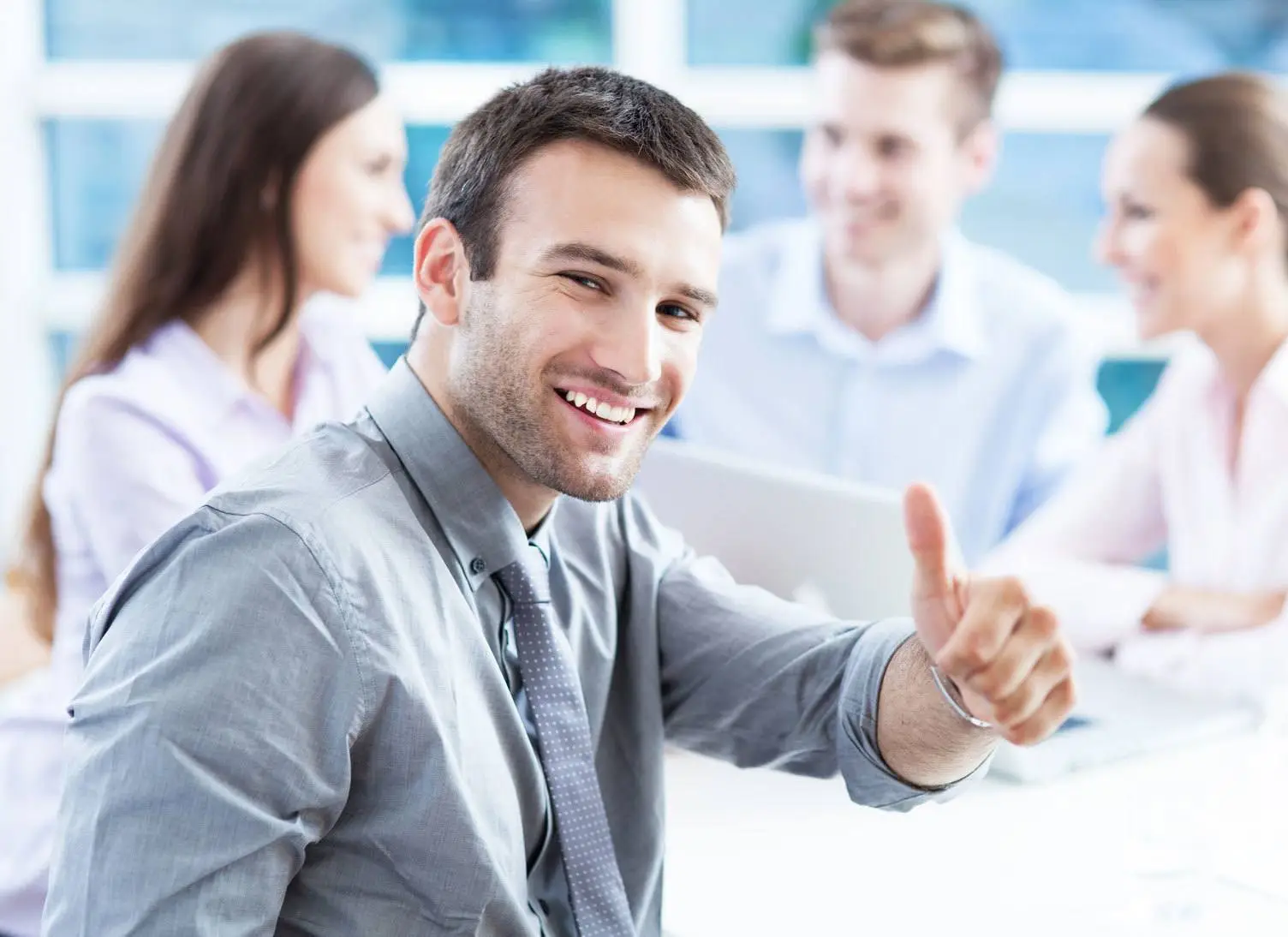 Information Technology Salary: Those Starting Out Will Get A Pay Increase In Top It Fields 4 confident young man in a modern office celebrates teamwork with a thumbs up.
