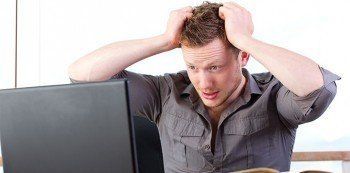 young man stressed at computer, showing the emotional toll of digital work challenges.
