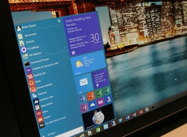 windows interface with start menu, weather widget, and cityscape background at night.