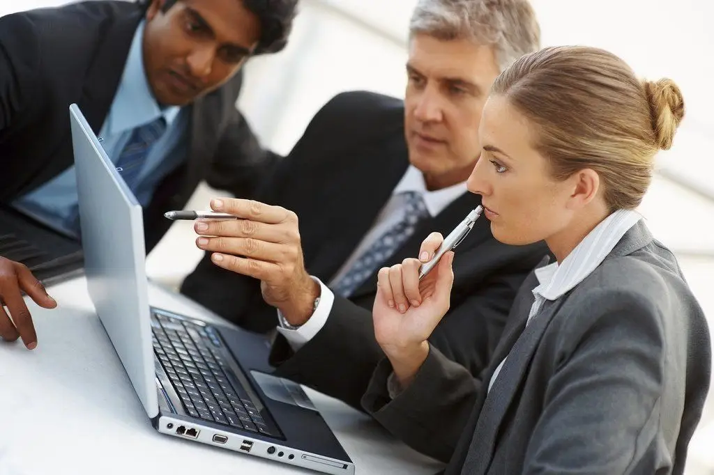 Optimize Your Business By Speeding Up Your Windows 10 Startup 3 three professionals collaborate on strategy in a modern office setting.