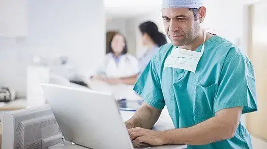 The Perks Of It Support For Doctor'S Offices 6 male doctor in scrubs utilizes laptop to enhance patient care in a hospital setting.