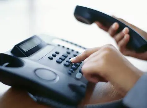 Remedies To Common Voip Problems 1 close-up of a hand dialing a number on a traditional office landline phone.