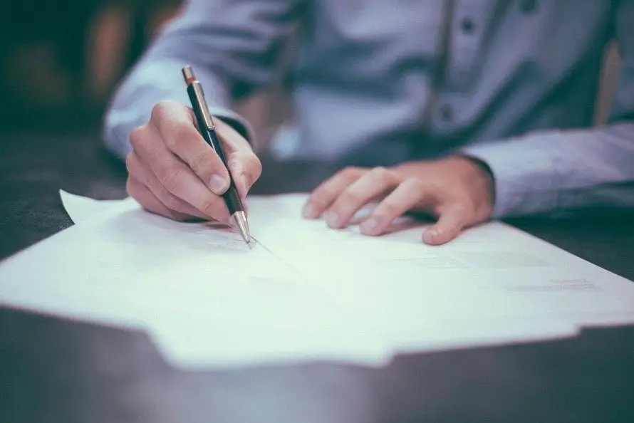 Get Document Management Consulting With Ae Technology Group 2 person in blue shirt writing notes on paper in a relaxed workspace.