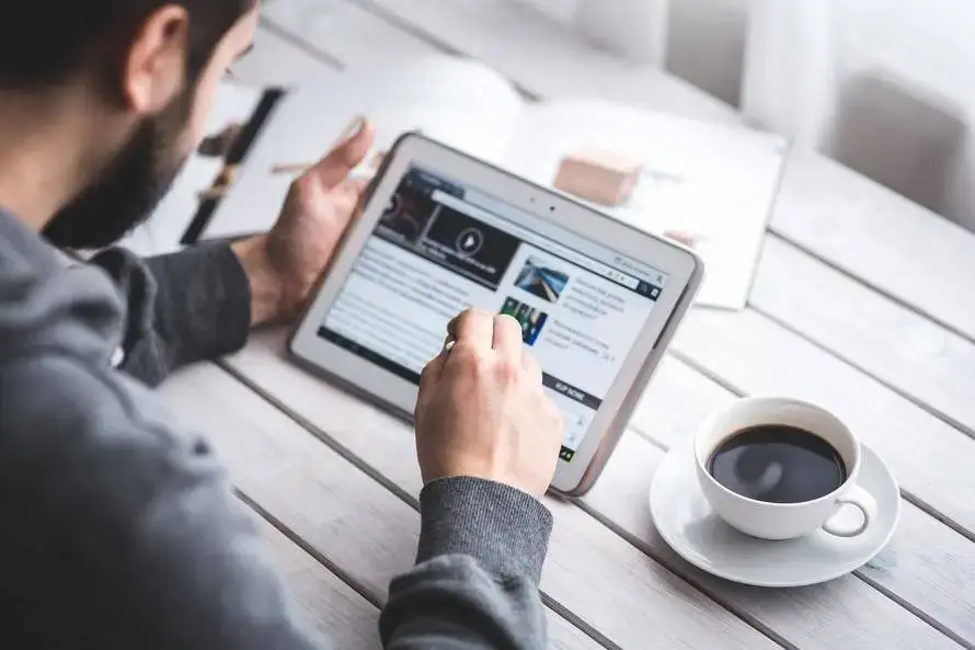 Enjoy The Benefits Of Remote Support 1 man enjoys coffee and tablet in a cozy, rustic setting with natural light.