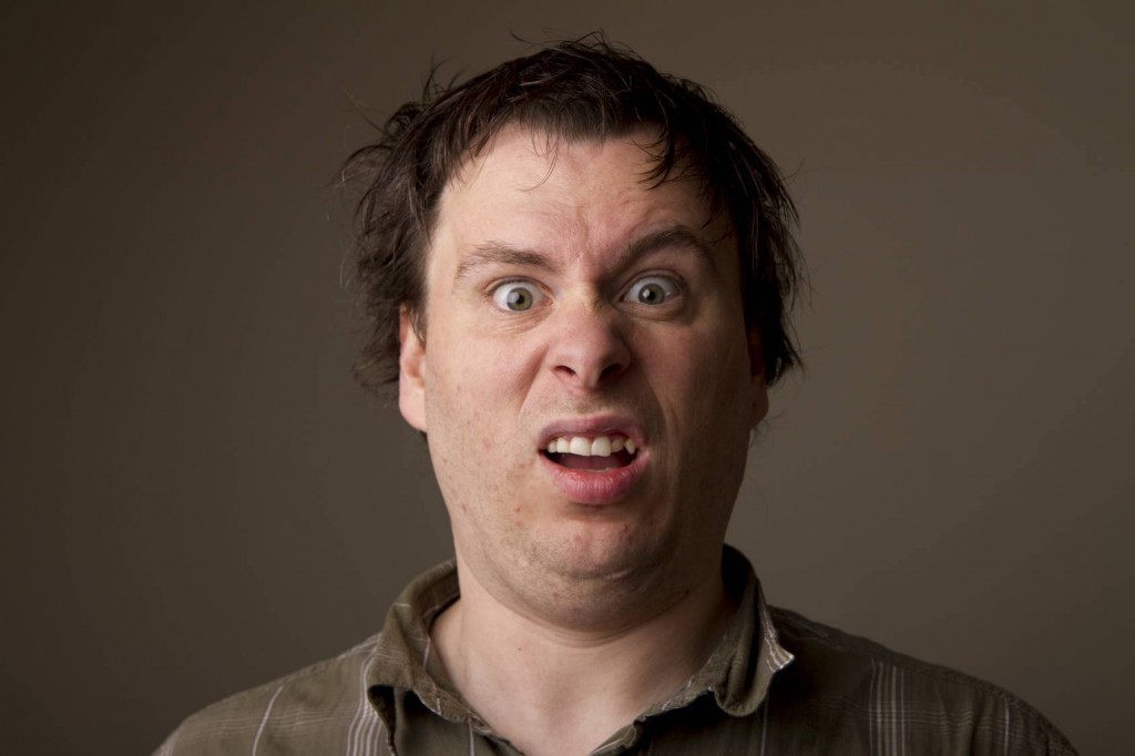 man showing strong confusion with wide eyes, furrowed brow, and grimace in close-up portrait.