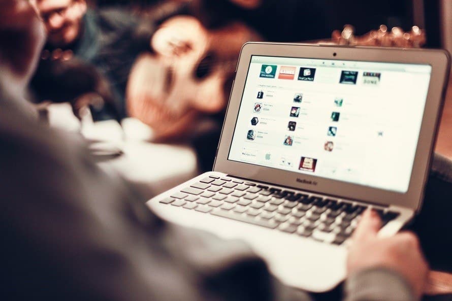 person engaging with a macbook in a cozy, social setting, highlighting technology and connection.