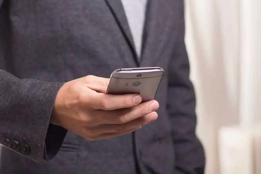 Get It Support On Long Island 3 professional in grey suit using smartphone in modern office setting.