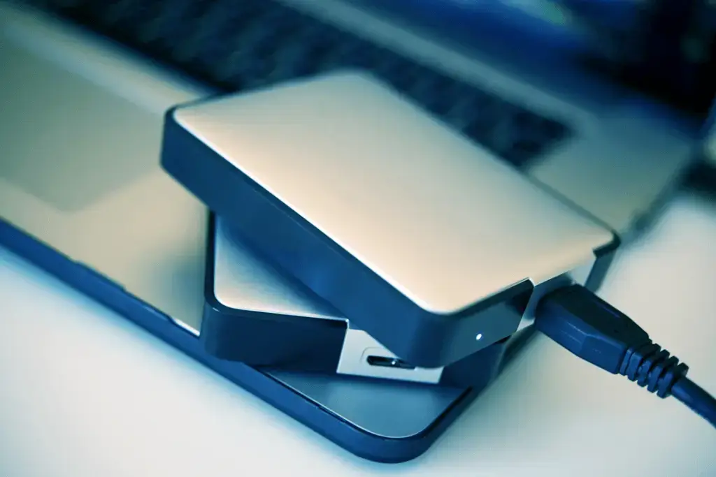 Computer Tip Of The Day: Backing Up Your Data 2 sleek external hard drive on laptop for secure data backup and efficient workspace management.