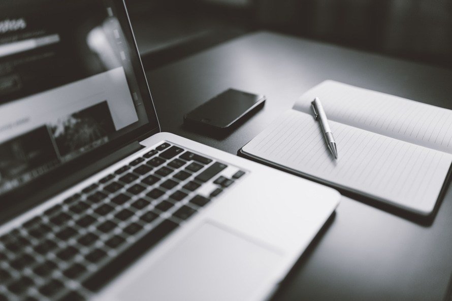 modern workspace featuring a laptop, smartphone, notebook, and pen for creative productivity.