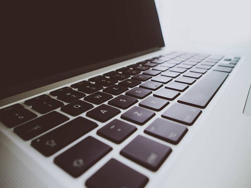 close-up of a sleek laptop keyboard with matte keys and reflective casing in soft lighting.