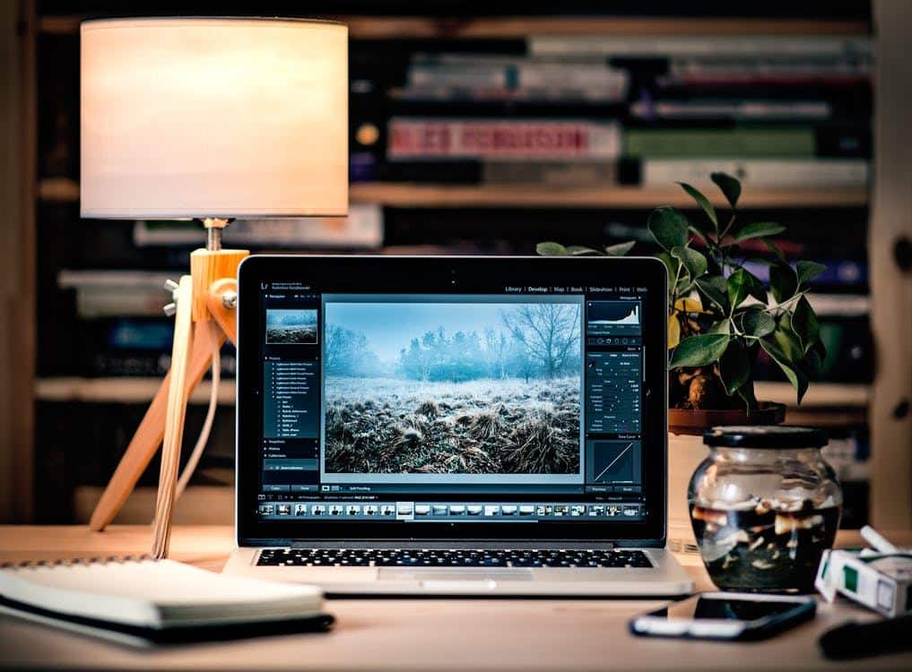 cozy workspace with laptop, notebook, plant, and warm lighting for creativity and focus.