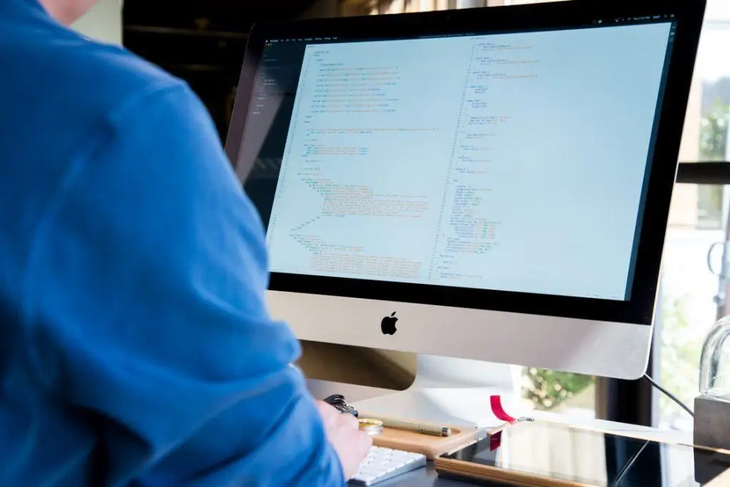 Individual coding on iMac, emphasizing password complexity for improved application security.