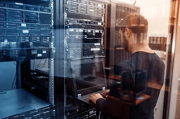 Technician troubleshooting in a sleek, organized server room illuminated by warm natural light.