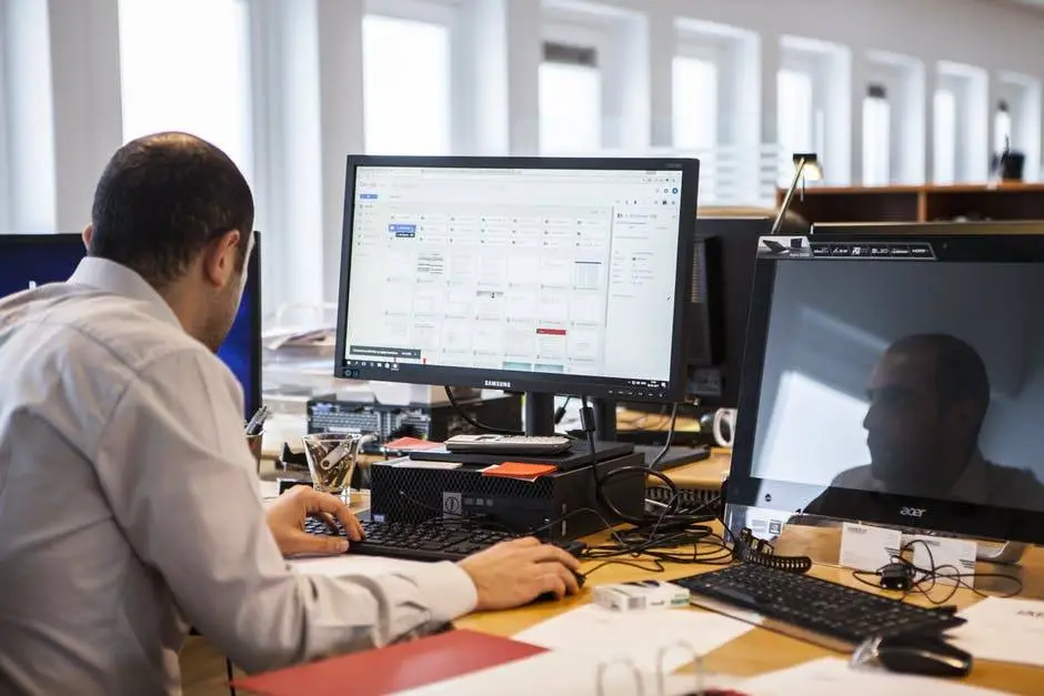 Get Away From The Computer Screen - Computer Tip Of The Day 5 focused professional working efficiently in a bright, modern office with dual monitors.