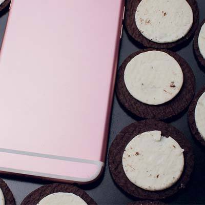 trendy pink smartphone surrounded by delicious oreo cookies, creating a cozy and inviting scene.