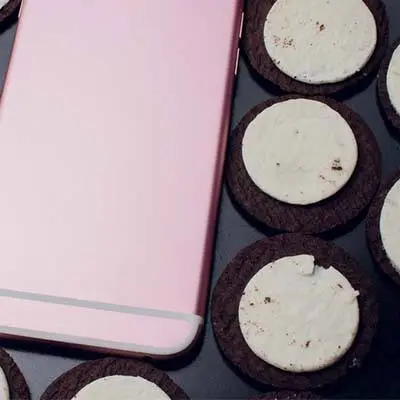 trendy pink smartphone surrounded by delicious oreo cookies, creating a cozy and inviting scene.