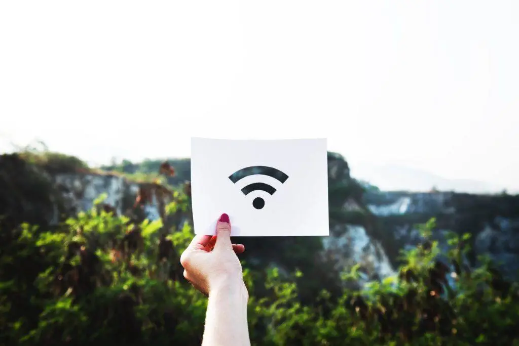 Computer Tip Of The Day: Internet Speed And Your Business 2 person displays a wi-fi symbol sign in a lush, natural landscape, blending technology with nature.
