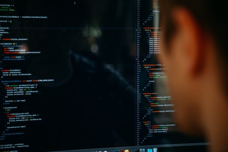 focused programmer immersed in colorful code on a dimly lit computer screen.