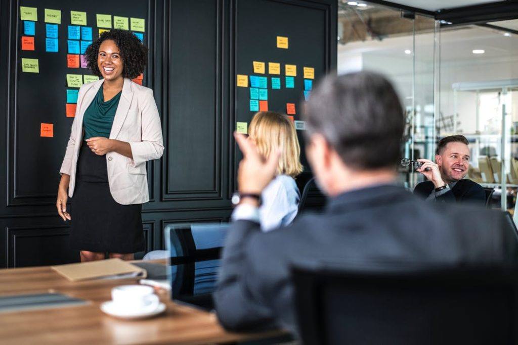 confident woman leads a creative team meeting surrounded by colorful sticky notes.