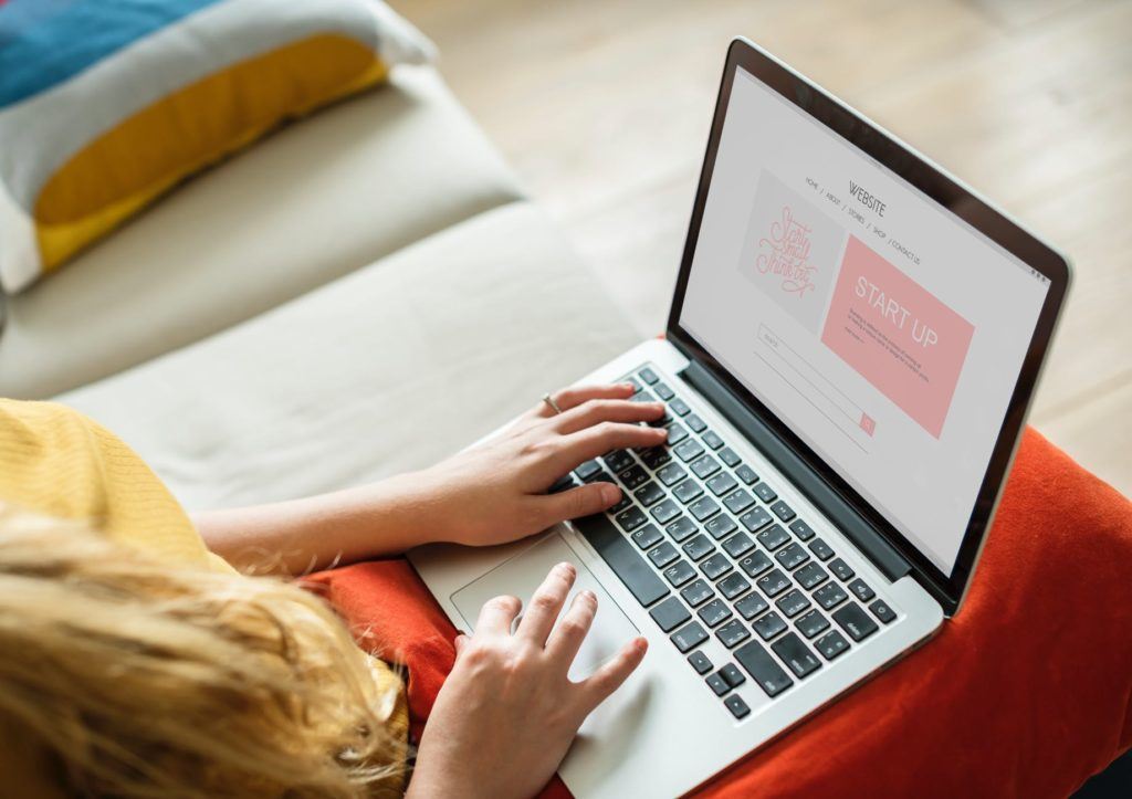 woman comfortably using a laptop on a sofa in a cozy, inviting home office.