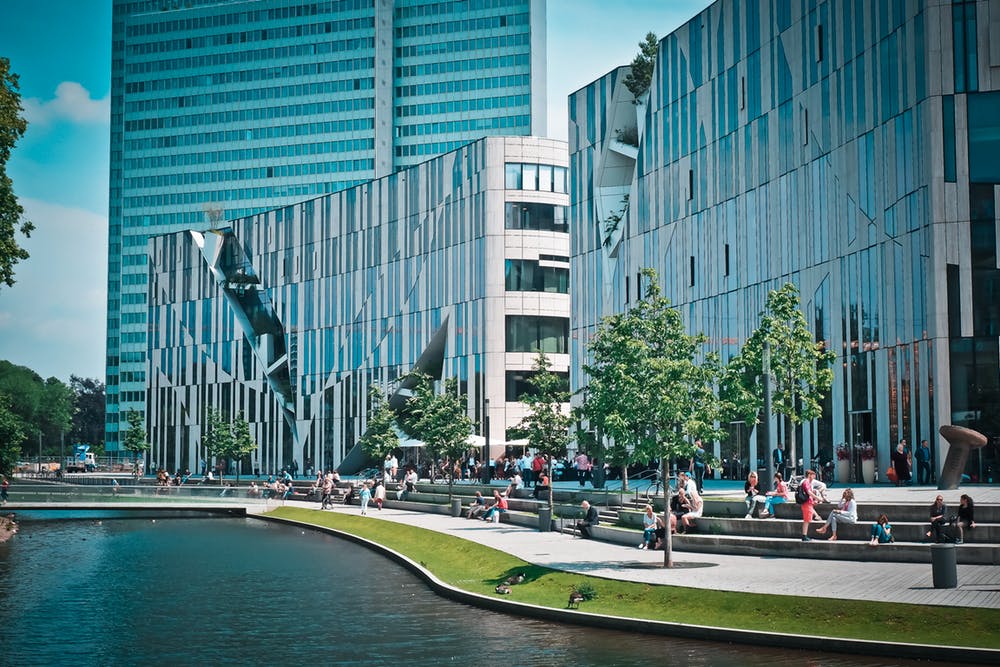 modern urban landscape featuring sleek buildings and a tranquil waterway with people enjoying outdoor activities.