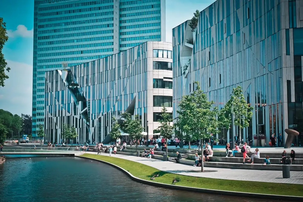 Have You Tested Your Disaster Recovery Plan? 6 modern urban landscape featuring sleek buildings and a tranquil waterway with people enjoying outdoor activities.