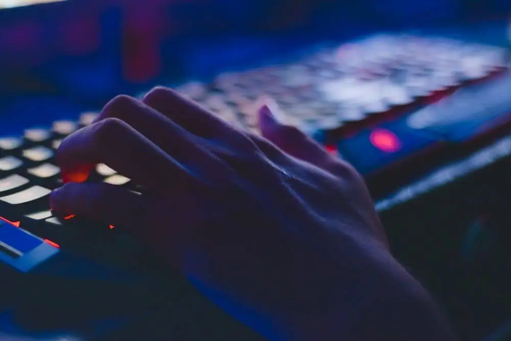 Increase Productivity By Utilizing New Technologies 5 close-up of a hand typing on a backlit keyboard in a dimly lit environment.