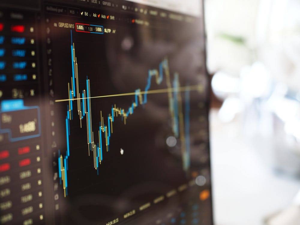 close-up of a candlestick chart depicting financial trends and trading metrics on a dark screen.