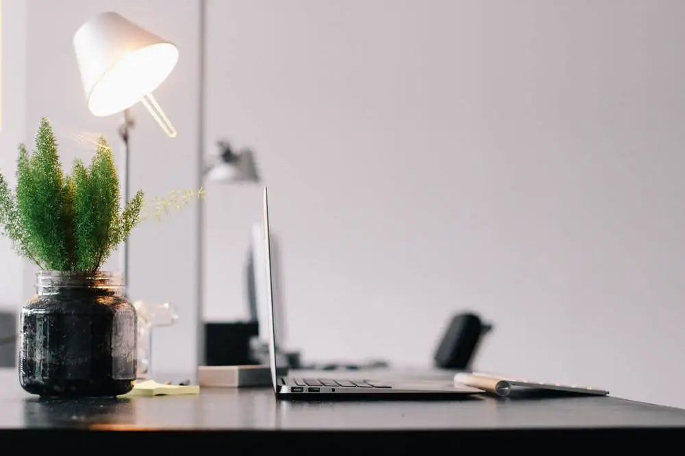 Ways To Get The Most From A Managed Help Desk 4 stylish modern workspace with a laptop, potted plant, and warm lighting for productivity.