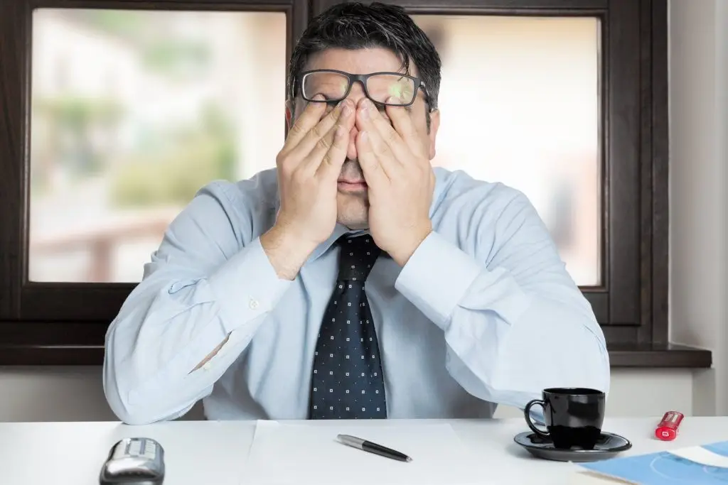 Business Continuity - How To Avoid Disaster In 6 Steps 2 stressed man at desk in bright office, struggling with overwhelming workload and frustration.