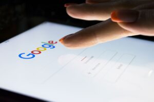A woman's hand is touching screen on tablet computer iPad pro at night for searching on Google search engine. Google is popular Internet search engine