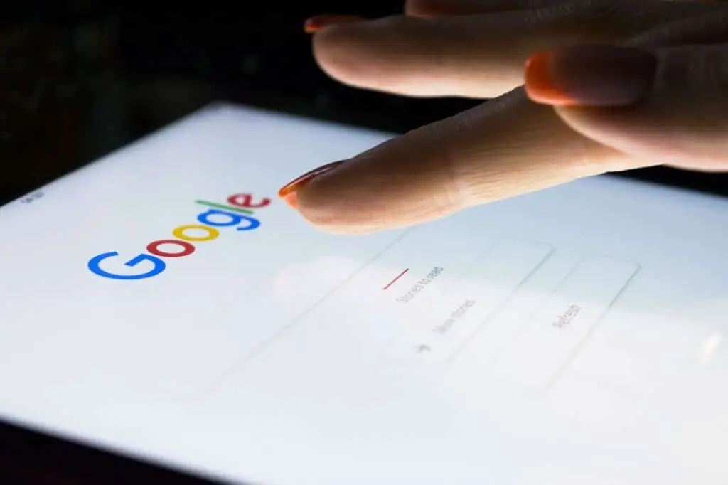 delicate hand poised over vibrant google search page on a tablet, ready for interaction.