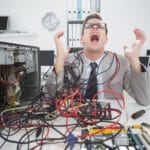 Stressed computer engineer working on broken cables screaming in frustration