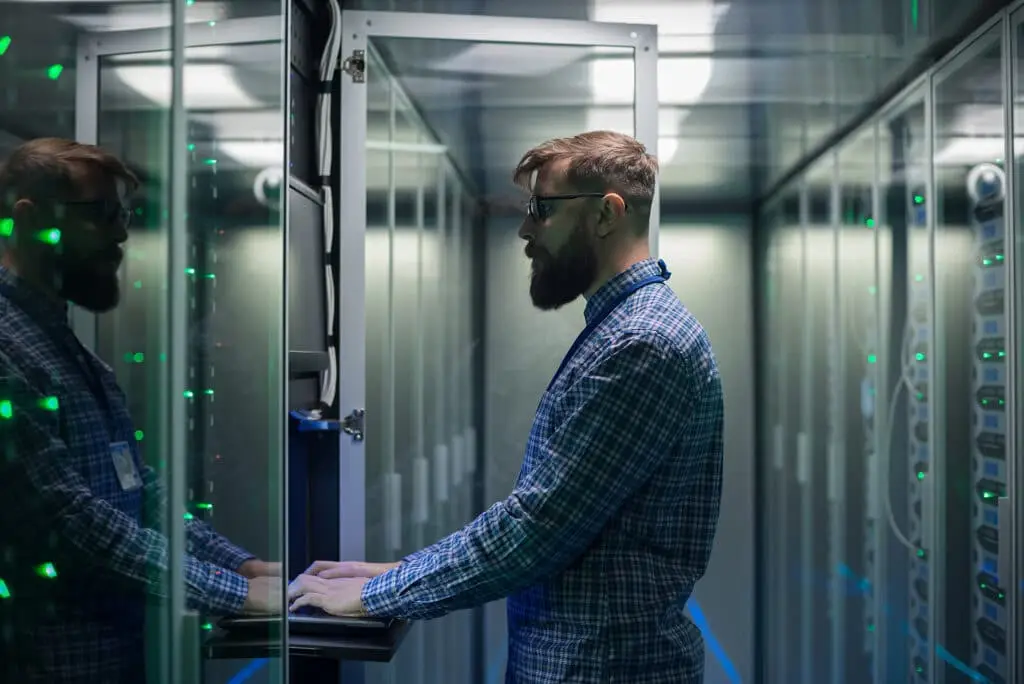 Network Maintenance 101 7 technician monitors server performance in a modern, high-tech data center.