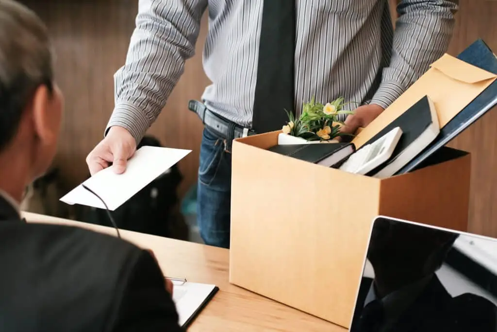 Businessman resigning with letter and personal items in an office setting.