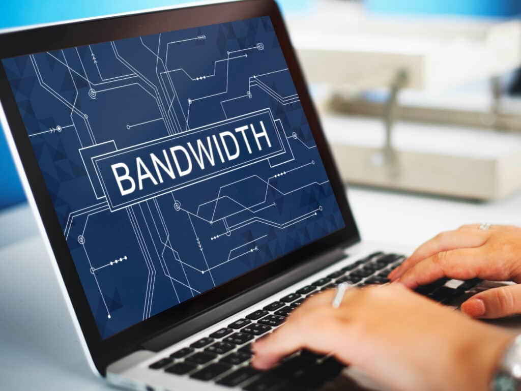 person typing on a laptop with bandwidth displayed, emphasizing digital connectivity and productivity.