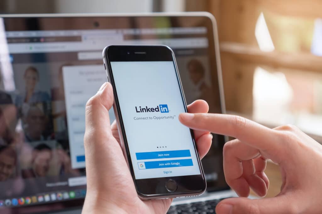 a person using an iphone x to access linkedin in a modern office setting.
