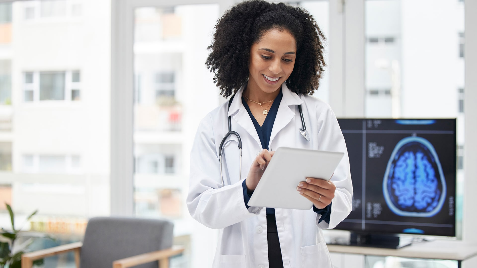 cheerful healthcare professional using a tablet in a bright, modern medical office.